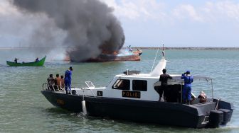 Petugas dari Kejaksaan Negeri Banda Aceh, Pengawasan Sumber Daya Kelautan dan Perikanan (PSDKP) dan personel Dit Pol Air Polda Aceh mengawasi jalannya eksekusi pemusnahan kapal penangkap ikan negara asing berbendera Malaysia di perairan Pelabuhan Samudera Lampulo, Banda Aceh, Aceh, Kamis (18/3/2021).  ANTARA FOTO/Irwansyah Putra