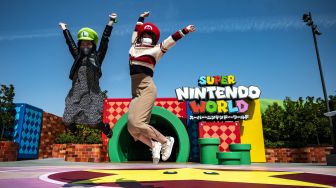 Penggemar Universal Studio Jepang berpose di pintu masuk Super Nintendo World, Osaka, Jepang, pada (17/3/2021). [Philip FONG / AFP]