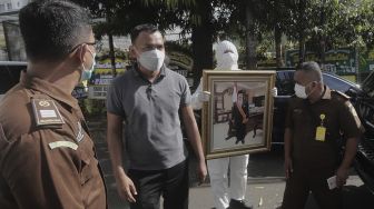 Salah satu anggota keluarga membawa foto Mantan Jaksa Agung Basrief Arief usai menyolatkan jenazahnya di rumah duka di kawasan Petogogan, Kebayoran Baru, Jakarta, Selasa (23/3/2021). [Suara.com/Angga Budhiyanto]