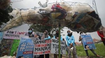 Aktivis lingkungan dari River Warrior dan Ecoton membentangkan poster saat berunjuk rasa menolak sampah asal Amerika Serikat masuk ke Indonesia di sekitar kantor Konsulat Jenderal Amerika Serikat di Surabaya, Jawa Timur, Kamis (25/3/2021). ANTARA FOTO/Moch Asim
