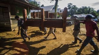 Sejumlah warga bergotong royong memikul rumah untuk di bawa ke makam saat tradisi membatur di Desa Ajung, Kabupaten Balangan, Kalimantan Selatan, Jumat (26/3/2021). [ANTARA FOTO/Bayu Pratama S]