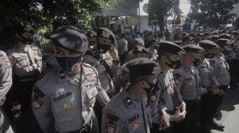 Petugas Kepolisian melakukan pengamanan saat berlangsungnya sidang lanjutan kasus pelanggaran protokol kesehatan dengan terdakwa Rizieq Shihab di depan Pengadilan Negeri (PN) Jakarta Timur, Jakarta, Jumat (26/3/2021). [Suara.com/Angga Budhiyanto]