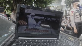 Laptop menampilkan suasana sidang kasus pelanggaran protokol kesehatan dengan terdakwa Rizieq Shihab di halaman Pengadilan Negeri (PN) Jakarta Timur, Jakarta, Jumat (26/3/2021). [Suara.com/Angga Budhiyanto]