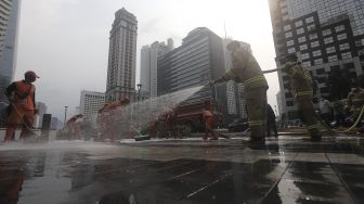 Petugas gabungan Unit Kerja Perangkat Daerah (UKPD) membersihkan trotoar sepanjang Jalan Sudirman-Thamrin, Jakarta, Sabtu (27/3/2021). [Suara.com/Angga Budhiyanto]