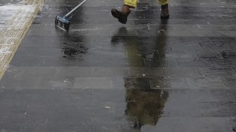 Petugas gabungan Unit Kerja Perangkat Daerah (UKPD) membersihkan trotoar sepanjang Jalan Sudirman-Thamrin, Jakarta, Sabtu (27/3/2021). [Suara.com/Angga Budhiyanto]