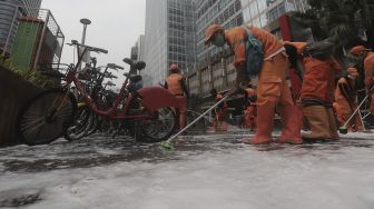 Petugas gabungan Unit Kerja Perangkat Daerah (UKPD) membersihkan trotoar sepanjang Jalan Sudirman-Thamrin, Jakarta, Sabtu (27/3/2021). [Suara.com/Angga Budhiyanto]