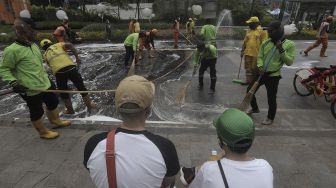 Petugas gabungan Unit Kerja Perangkat Daerah (UKPD) membersihkan trotoar sepanjang Jalan Sudirman-Thamrin, Jakarta, Sabtu (27/3/2021). [Suara.com/Angga Budhiyanto]