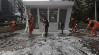 Petugas gabungan Unit Kerja Perangkat Daerah (UKPD) membersihkan trotoar sepanjang Jalan Sudirman-Thamrin, Jakarta, Sabtu (27/3/2021). [Suara.com/Angga Budhiyanto]