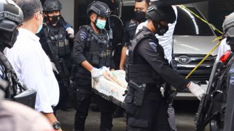 Petugas Brimob membawa temuan barang bukti berupa bahan peledak saat melakukan penggeledahan di rumah terduga teroris di Condet, Jakarta Timur, Senin (29/3/2021). [Suara.com/Alfian Winanto]