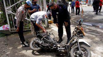 Anggota polisi mengamati motor yang digunakan terduga pelaku bom bunuh diri sebelum dievakuasi di depan Gereja Katedral Makassar, Sulawesi Selatan, Senin (29/3/2021). ANTARA FOTO/Arnas Padda