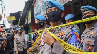 Petugas Kepolisian memasang garis polisi di sekitar rumah terduga teroris di kawasan Condet, Jakarta Timur, Senin (29/3/2021). [Suara.com/Alfian Winanto]