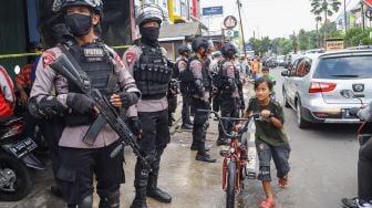 Petugas Brimob berjaga di depan rumah terduga teroris di kawasan Condet, Jakarta Timur, Senin (29/3/2021). [Suara.com/Alfian Winanto]