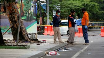 Anggota polisi mengumpulkan sisa serpihan ledakan bom bunuh diri di depan Gereja Katedral Makassar, Sulawesi Selatan, Senin (29/3/2021). ANTARA FOTO/Arnas Padda
