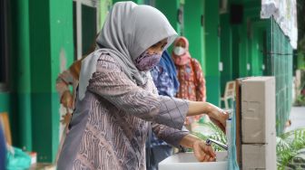 Orang Tua murid  mencuci tangan saat melaksanakan simulasi sekolah tatap muka Hybrid di SMP Negeri 255, Jakarta Timur, Selasa (30/3/2021). [Suara.com/Alfian Winanto]