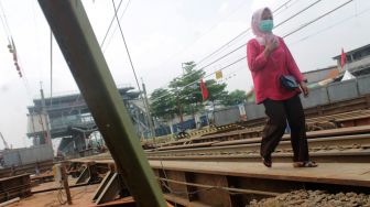 Pejalan kaki melewati jembatan rel kereta, Kecamatan Cibitung, Kabupaten Bekasi, Rabu (31/03/21). [Suara.com/Dian Latifah]