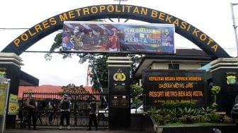 Petugas berjaga di depan pintu gerbang masuk Polres Metro Bekasi Kota, Kota Bekasi, Kamis (01/04/21).  [Suara.com/Dian Latifah]