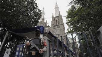 Personel kepolisian berjaga di depan Gereja Katedral, Jakarta, Kamis (1/4/2021). [Suara.com/Angga Budhiyanto]