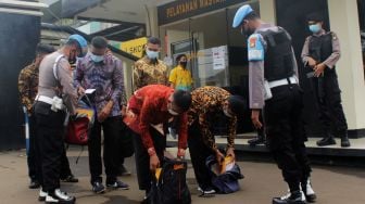 Petugas kepolisian memeriksa barang bawaan pendaftar anggota polri di Polres Metro Bekasi Kota, Kota Bekasi, Kamis (01/04/21). [Suara.com/Dian Latifah] 