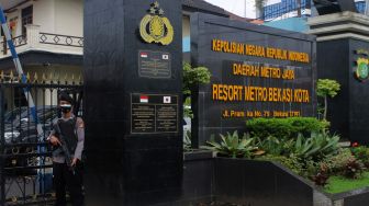 Petugas memegang laras panjang berjaga di depan pintu gerbang masuk Polres Metro Bekasi Kota, Kota Bekasi, Kamis (01/04/21). [Suara.com/Dian Latifah]    