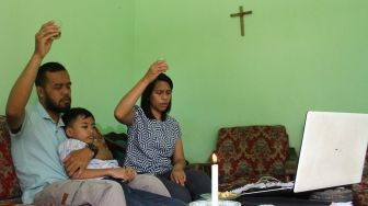 Umat Kristen Protestan mengikuti ibadah Jumat Agung dalam rangkaian Perayaan Paskah secara daring di rumahnya, Ngijo, Karangploso, Malang, Jawa Timur, Jumat (2/4/2021).  ANTARA FOTO/Ari Bowo Sucipto