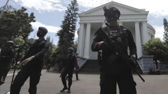 Petugas kepolisian berjaga saat melakukan pengamanan dan sterilisasi di sela berlangsungnya misa Jumat Agung menjelang hari raya Paskah di Gereja Immanuel, Jakarta, Jumat (2/4/2021). [Suara.com/Angga Budhiyanto]