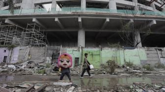 Pengamen berjalan melintasi di Kampung Bayam, Papanggo, Tanjung Priok, Jakarta Utara, Sabtu (3/4/2021). [Suara.com/Angga Budhiyanto]