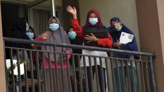 Sejumlah siswi yang dikarantina melambaikan tangan saat penyemprotan disinfektan di asrama SMAN 1 Sumatera Barat, di Kota Padangpanjang, Sabtu (3/4/2021). [ANTARA FOTO/Iggoy el Fitra]