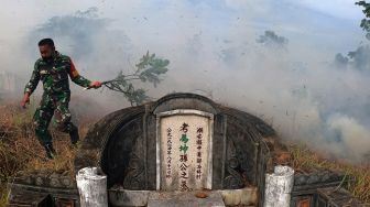 Warga menghindari asap usai mencoba memadamkan api yang membakar areal sekitar kuburan Cina saat pelaksanaan tradisi ceng beng (ziarah kubur) di Jambi, Minggu (4/4/2021). ANTARA FOTO/Wahdi Septiawan
