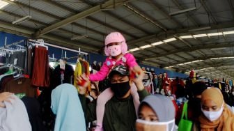 Seorang anak kecil yang digendong oleh orang tuanya saat berada di Skybridge Pasar Tanah Abang, Jakarta, Minggu (04/04/21). [Suara.com/Dian Latifah]
