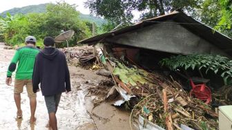 Warga melintas di dekat rumah yang rusak akibat banjir bandang di Adonara Timur, Flores Timur, NTT, Senin (5/4/2021).  ANTARA FOTO
