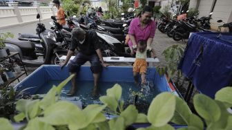 Warga melakukan terapi menggunakan ikan (fish spa) di ruang edukasi anak di halaman Kantor Kelurahan Karet, Jakarta, Rabu (7/4/2021). [Suara.com/Angga Budhiyanto]