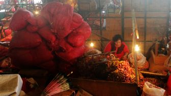 Seorang Ibu melakukan aktivitas mengupas bawang diatas kiosnya yang berda di Pasar Induk Kramat Jati, Jakarta Timur, Rabu (07/4/21). [Suara.com/Dian Latifah]  