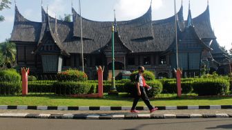 Pengunjung berjalan melewati anjungan rumah adat Sumatera Barat di TMII, Jakarta Timur, Kamis (08/4/21). [Suara.com/Dian Latifah]