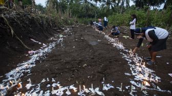 Sejumlah warga menyalakan lilin saat berziarah di tempat pemakaman massal korban tanah longsor di Desa Nelelamadike, Kecamatan Ile Boleng, Kabupaten Flores Timur, Nusa Tenggara Timur (NTT), Rabu (7/4/2021).  ANTARA FOTO/Aditya Pradana Putra