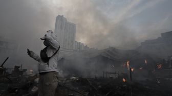 Seorang warga mengambil gambar kebakaran yang melanda Pasar Lontar atau Pasar Kambing di Jalan Sabeni, Tanah Abang, Jakarta, Kamis (8/4/2021). [Suara.com/Angga Budhiyanto]