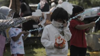 Siswa taman kanak-kanak (TK) menunjukkan miniatur beduk buatannya saat mengikuti proses pembelajaran secara Drive in Learning (DRIL) di area parkir Padepokan Pencak Silat Indonesia, Jakarta, Kamis (8/4/2021). [Suara.com/Angga Budhiyanto]