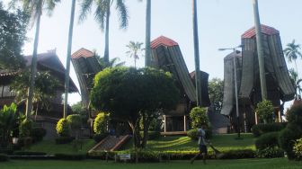 Petugas membersihkan anjungan rumah adat di TMII, Jakarta Timur, Kamis (08/4/21). [Suara.com/Dian Latifah]