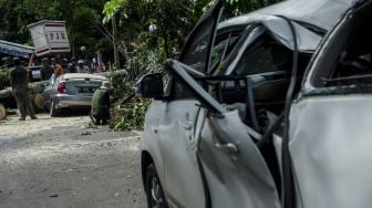 Petugas Dinas Perumahan dan Kawasan Permukiman, Pertanahan dan Pertamanan (Dpkp3) Kota Bandung mengevakuasi pohon tumbang yang menimpa mobil di Bandung, Jawa Barat, Kamis (8/4/2021). ANTARA FOTO/Novrian Arbi

