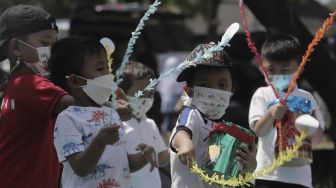 Sejumlah siswa taman kanak-kanak (TK) menunjukkan miniatur beduk buatannya saat mengikuti proses pembelajaran secara Drive in Learning (DRIL) di area parkir Padepokan Pencak Silat Indonesia, Jakarta, Kamis (8/4/2021). [Suara.com/Angga Budhiyanto]