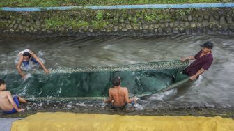 Sejumlah warga bergotong royong membilas karpet mushalla usai dicuci di Karanganyar, Kabupaten Pekalongan, Jawa Tengah, Jumat (9/4/2021). [ANTARA FOTO/Harviyan Perdana Putra]