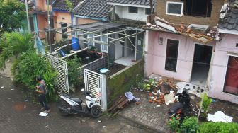 Seorang warga melintas di depan rumah yang rusak akibat gempa di Majangtengah, Malang, Jawa Timur, Minggu (11/4/2021).  ANTARA FOTO/Ari Bowo Sucipto

