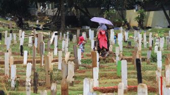 Warga usai ziarah di  area pemakaman khusus Covid - 19 TPU Bambu Apus, Jakarta Timur, Minggu (11/4/2021). [Suara.com/Alfian Winanto]