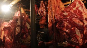 Pedagang menggantung daging di Pasar Bantargebang, Kota Bekasi, Minggu (11/4/2021). [Suara.com/Dian Latifah] 
