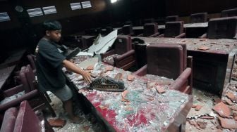 Petugas membersihkan puing-puing yang runtuh di Ruang Sidang Paripurna DPRD Kabupaten Blitar akibat gempa bumi di Blitar, Jawa Timur, Sabtu (10/4/2021).  ANTARA FOTO/Irfan Anshori
