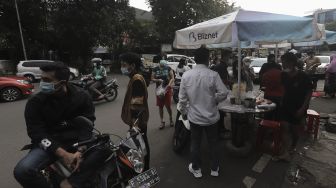 Pedagang melayani pembeli takjil dan makanan berbuka puasa di Pasar Takjil Benhil, Jakarta, Selasa (13/4/2021). [Suara.com/Angga Budhiyanto]