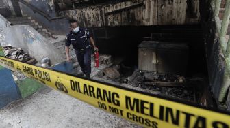 Petugas keamanan mengecek sisa-sisa kebakaran di Pasar Minggu, Jakarta, Selasa (13/4/2021). [Suara.com/Angga Budhiyanto]