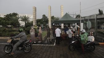 Petugas membagikan takjil kepada pengendara sepeda motor dengan sistem drive thru di kompleks Masjid Al-Azhar, Jakarta, Rabu (14/4/2021). [Suara.com/Angga Budhiyanto]