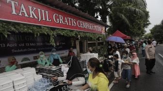 Sejumlah warga mengambil takjil gratis di jalan Cempaka Putih Tengah XXI, Jakarta, Kamis (15/4/2021). [Suara.com/Angga Budhiyanto]