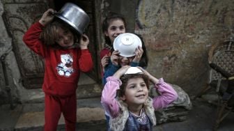 Anak-anak membawa mangkok agar mendapatkan sup gratis untuk berbuka puasa di tengah pandemi Covid-19 di Gaza, Palestina, Rabu (14/4). MOHAMMED ABED / AFP