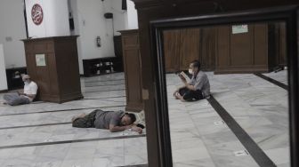 Refleksi umat Islam membaca Al-Quran di Masjid Cut Meutia, Menteng, Jakarta, Jumat (16/4/2021). [Suara.com/Angga Budhiyanto]